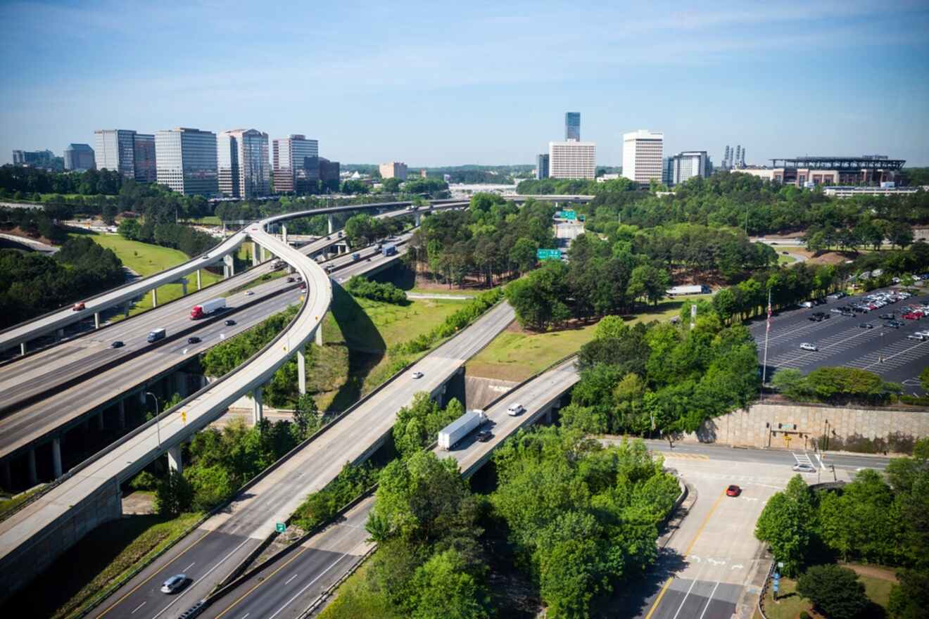Atlanta skyline with highways and overpasses in the foreground, lush greenery, and a mix of commercial buildings in the background.