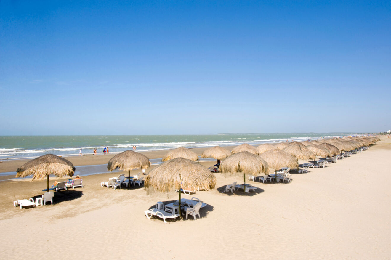 Deserted tropical beach in La Boquilla, Cartagena with thatched umbrellas and white sunbeds overlooking a serene ocean