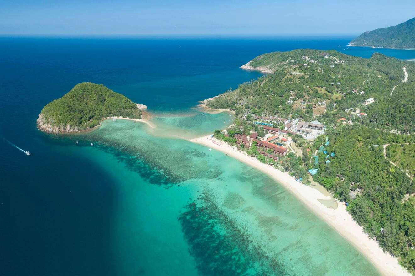 Aerial view of Koh Ma, a small tropical island connected by a sandbar to Mae Haad Beach on Koh Phangan, with clear turquoise waters and vibrant coral reefs