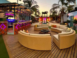 Vibrant outdoor lounge with circular seating and ambient lighting, adjacent to a colorful bar