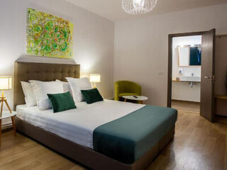 A serene and sophisticated hotel room with a comfortable bed, wooden floors, tasteful artwork, and soft lighting