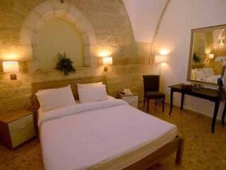 Elegant hotel room with arches, soft lighting, and a classic decor featuring a large double bed with white bedding.