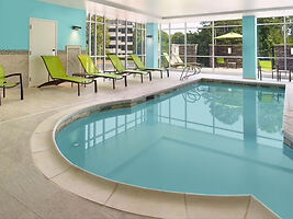 Indoor hotel pool with tranquil blue water and lime green lounge chairs, creating a relaxing atmosphere under an enclosure