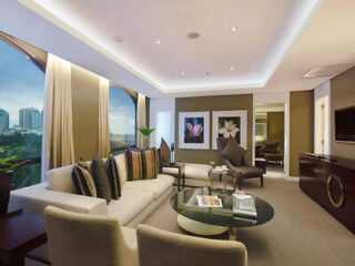 Luxurious living room in a hotel suite with plush sofas, a glass coffee table, and panoramic city views at twilight