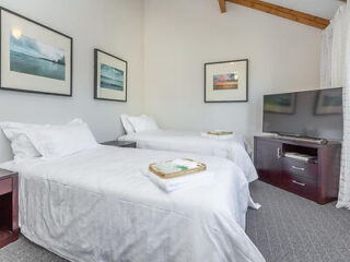 A bright and welcoming motel room with twin beds, crisp white linen, and sea-themed artwor