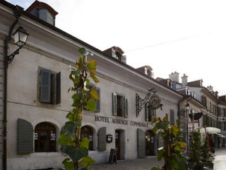 The historic façade of Hotel Auberge Communale in Carouge, featuring traditional architecture and street lamps