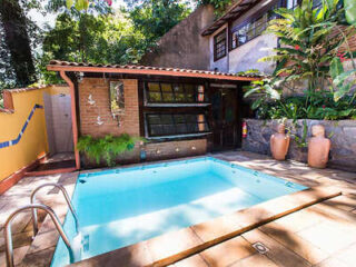 Quaint and serene backyard pool of O Veleiro B&B surrounded by lush greenery and a cozy guesthouse