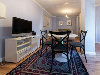A cozy dining area in a modern apartment, with a wooden table and black chairs on a decorative rug