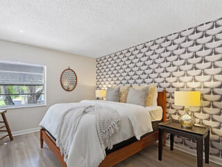 Bedroom with a distinctive black and white scalloped feature wall, warm wooden furniture, and decorative wall hangings