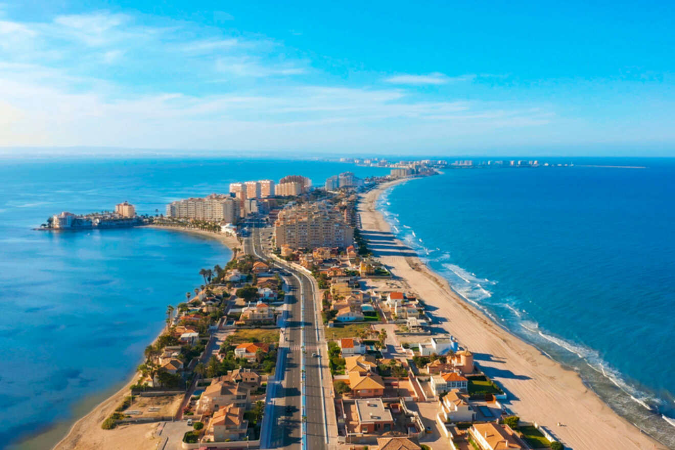 Aerial view of a narrow strip of land in Manga, Cartagena with beachfront homes and buildings on either side, bordered by the sea and a calm lagoon