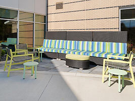 Bright patio seating area with vibrant blue and green striped benches, matching green chairs