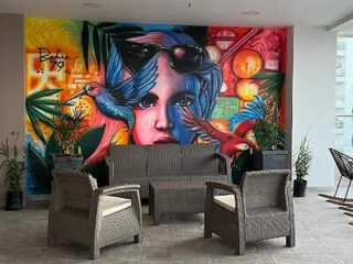 Cozy patio with wicker furniture against a colorful mural of a woman and birds