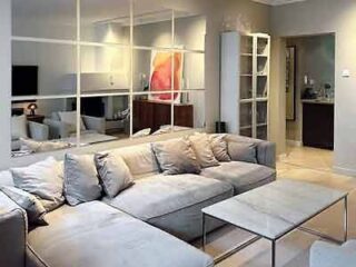 Spacious living room with a large gray sectional sofa, minimalist decor, and a large abstract painting adding a splash of color.