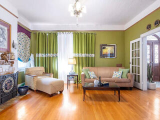 Vintage-inspired living space with hardwood floors, green walls, and eclectic furniture and decor