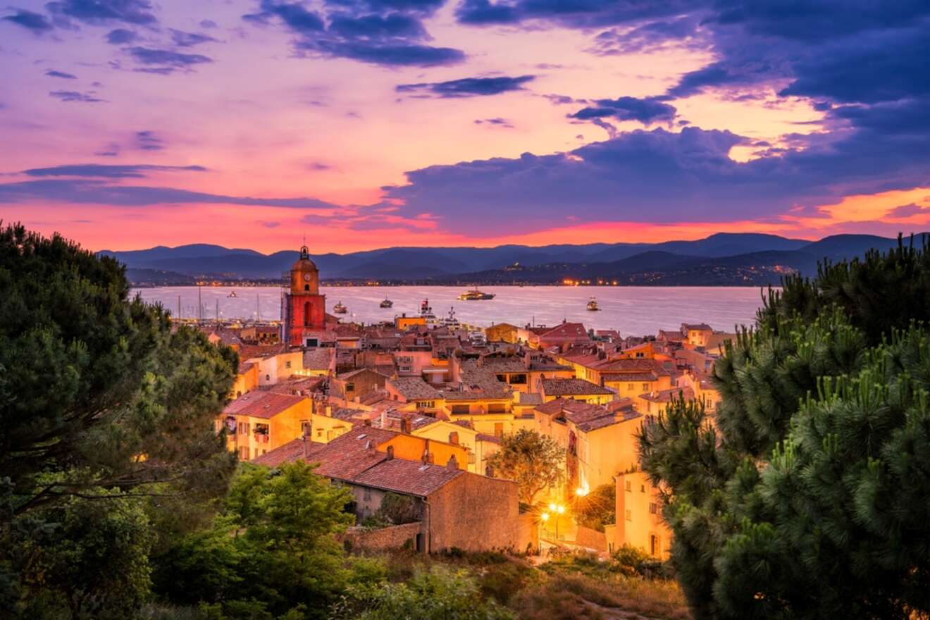 A stunning sunset view over the old town of Saint-Tropez, with warm lights illuminating the historic buildings and the bay reflecting the colorful sky