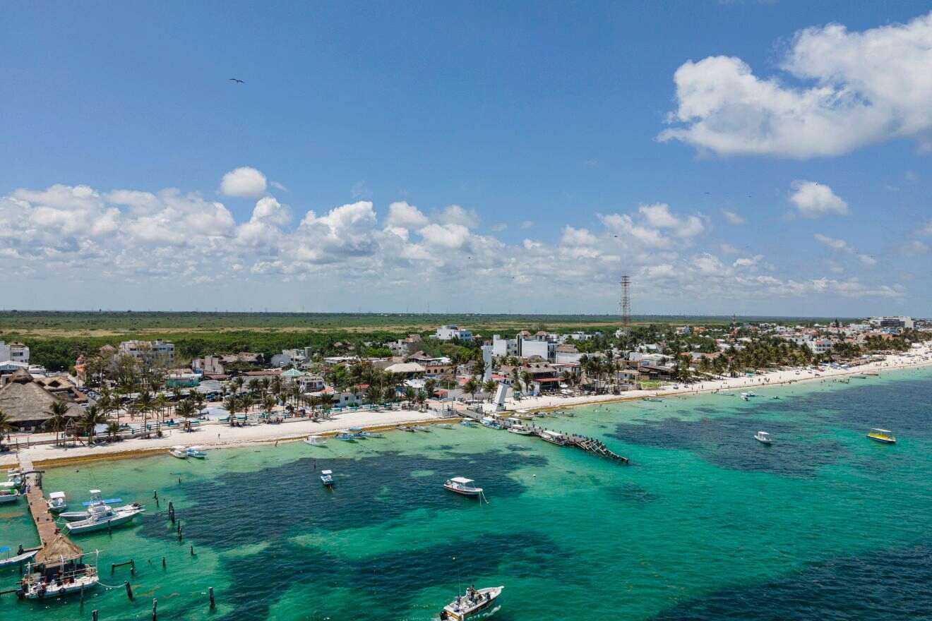 Aerial shot of Puerto Morelos with boats docked along the vibrant coastline, highlighting the peaceful charm of this fishing village turned tourist destination near Cancun