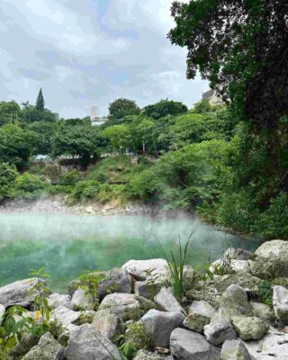 The misty waters and rocky edges of a hot spring in Beitou district, with verdant foliage surrounding this natural geothermal wonder.