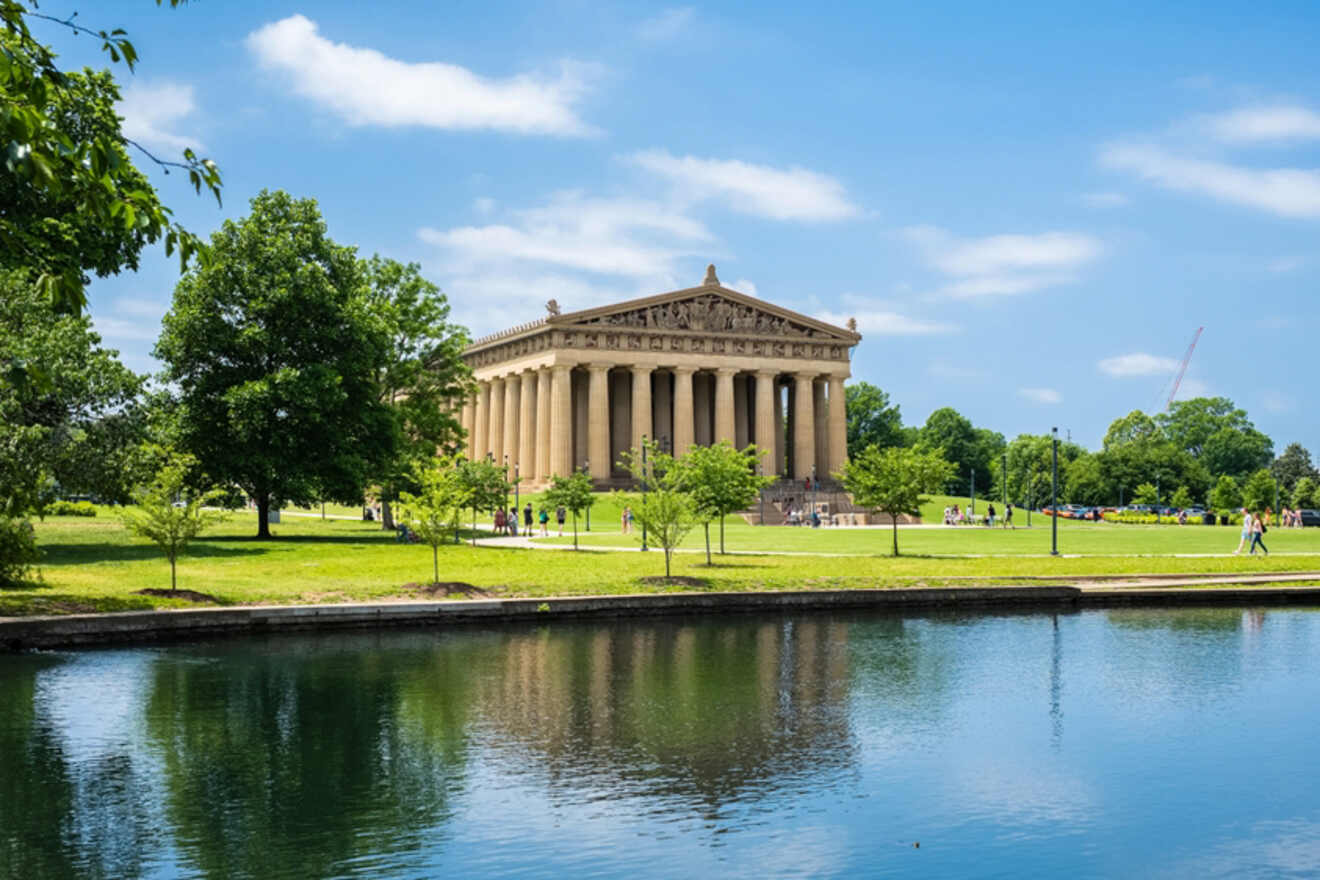 The iconic Parthenon in Nashville's Centennial Park, viewed across a tranquil lake with lush trees and clear skies