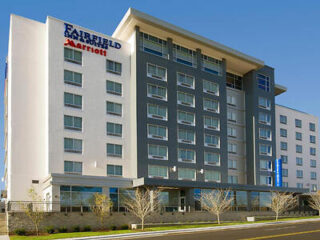 Facade of the Fairfield Inn & Suites hotel, showcasing a modern design with a mix of grey and white tones