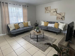 Inviting living room with two gray sofas, a round wood coffee table, and a decorative gray area rug on tiled flooring
