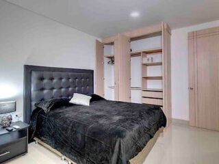 Modern bedroom featuring a luxurious black velvet bedspread, a tufted headboard, and an organized closet space