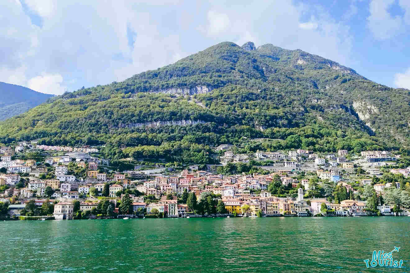 Idyllic view of Lake Como's waterside homes and terraced gardens against a backdrop of green mountains under a clear blue sky