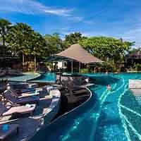 Inviting resort swimming pool surrounded by lush tropical greenery with loungers and a traditional Thai-style gazebo, reflecting a serene vacation atmosphere in Thailand.