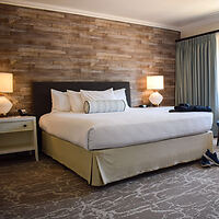 Elegant bedroom with a king-sized bed, wooden accent wall, and soft lighting for a cozy atmosphere.
