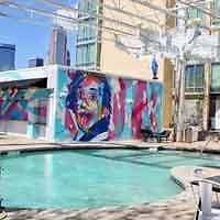 Urban hotel pool area with a vibrant, colorful mural on the wall, reflecting a lively and artistic atmosphere.