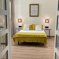 Contemporary bedroom with a queen-sized bed, mustard yellow bedding, matching pillows, and minimalist decor