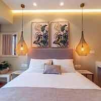 Elegant hotel room with twin pendant lights and botanical art over the bed