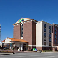 Exterior of a Holiday Inn Express hotel showcasing its classic design with the brand's green and white signage, under a clear blue sky