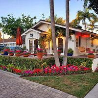 Charming motel facade with lush landscaping and welcoming porch at dusk.