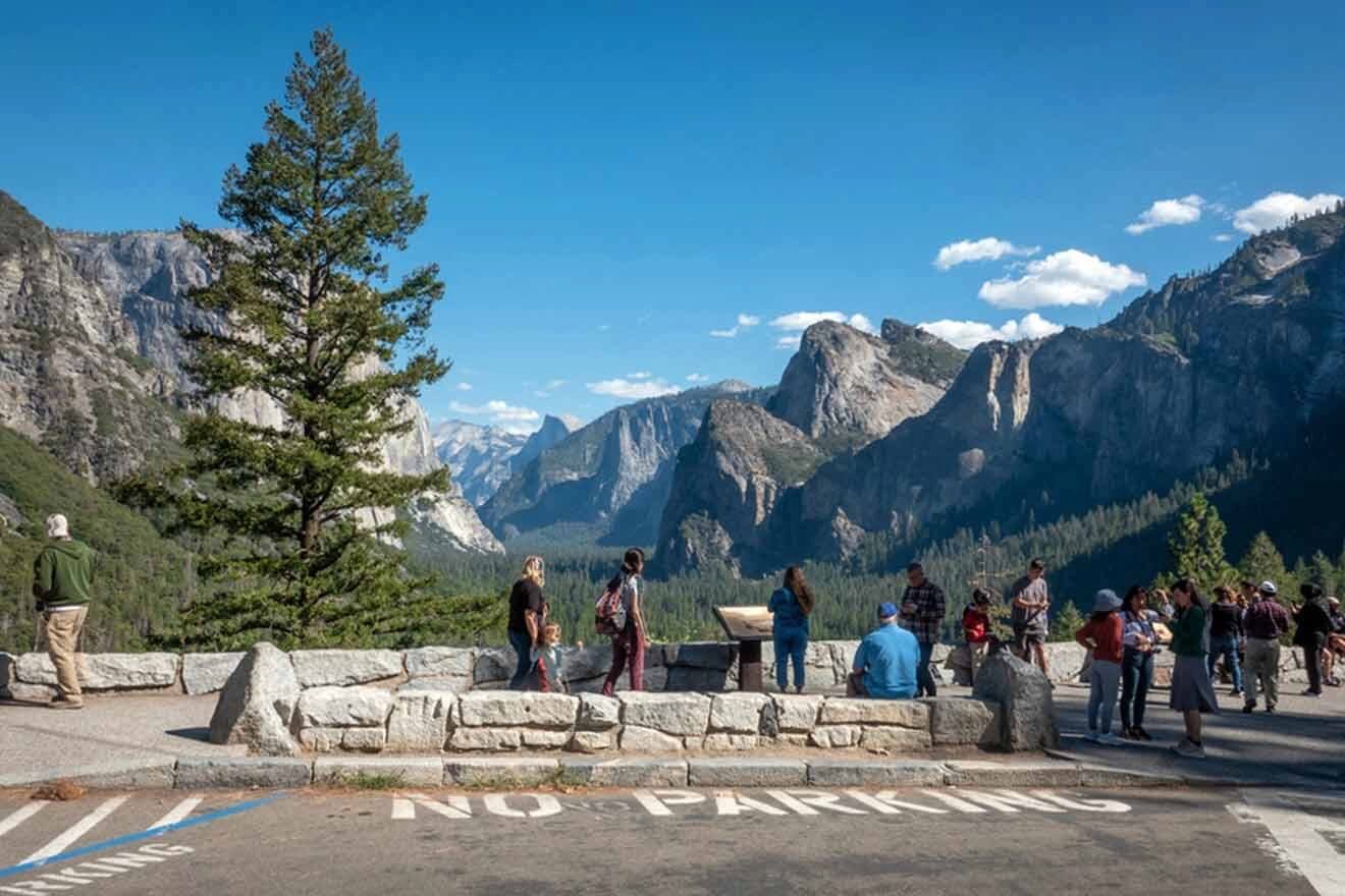 Visitors at an overlook in Yosemite with a "NO PARKING" sign on the pavement, enjoying the view of the valley and granite cliffs.
