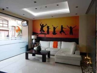 A modern living room with a white sofa, black coffee table, and an art piece depicting silhouetted figures dancing against an orange background.