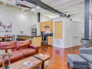 A spacious loft-style apartment with comfortable leather sofas, an open-plan kitchen, and a warm, inviting ambiance.