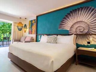 Elegantly decorated bedroom with a large bed and teal accent wall featuring a decorative shell pattern at Caribe Deluxe Princess.