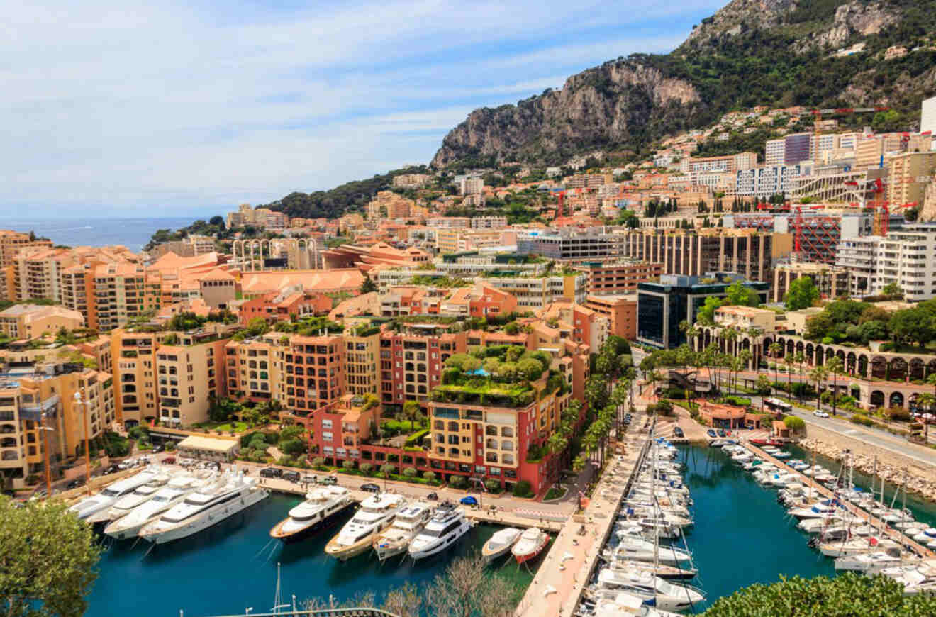 Scenic view of Monaco, with luxury yachts docked in a marina, surrounded by densely packed terracotta-roofed buildings and the Mediterranean Sea