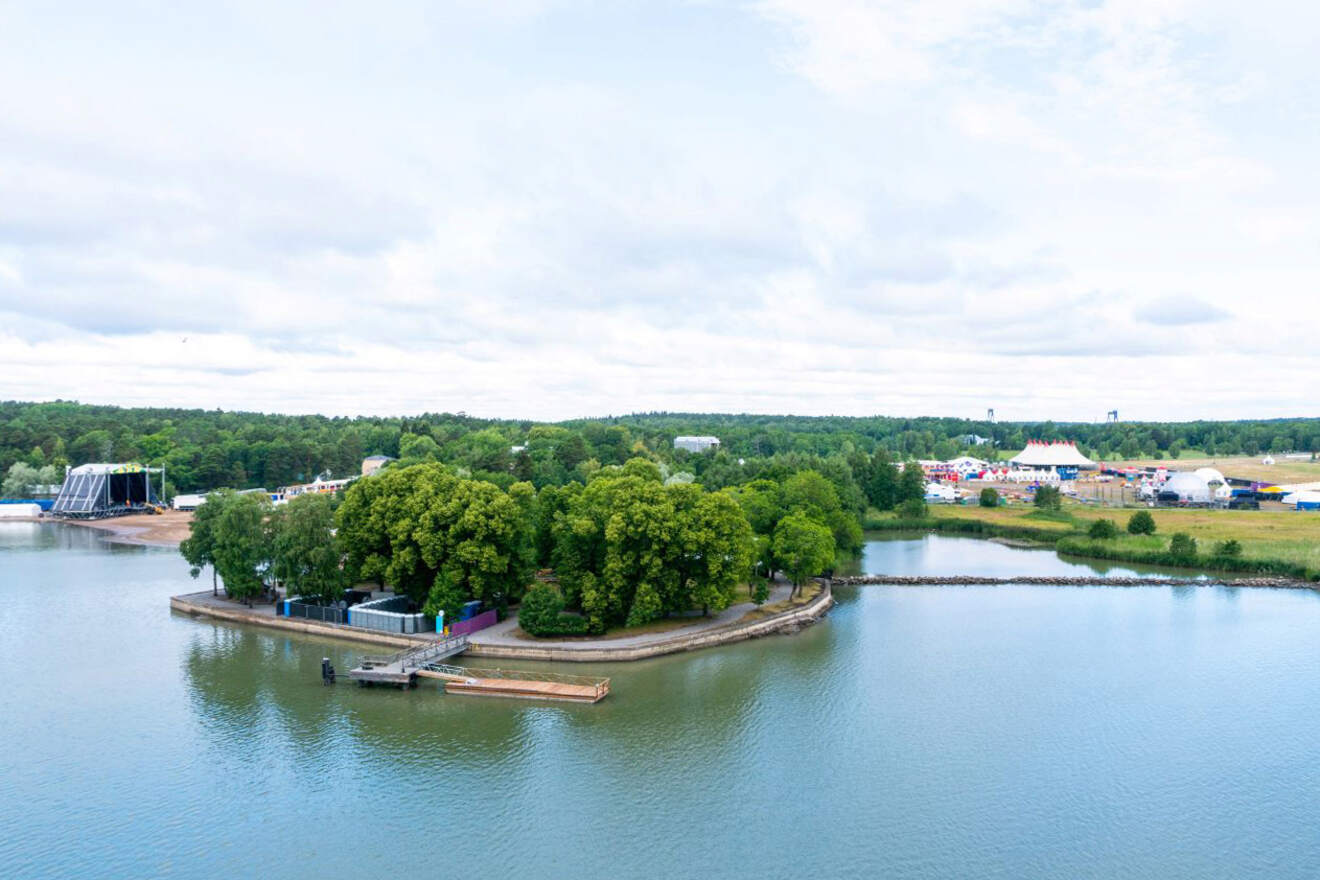 Aerial view of the lush Ruissalo Island in Turku, showcasing a festival setup with tents and stages beside calm waters