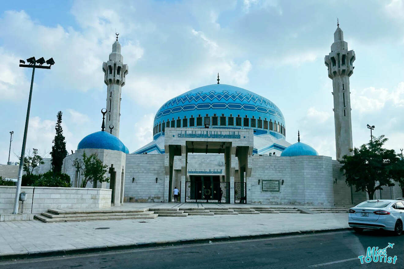 The King Abdullah Mosque in Amman, Jordan, distinguished by its large blue dome and tall minarets, set against a clear blue sky