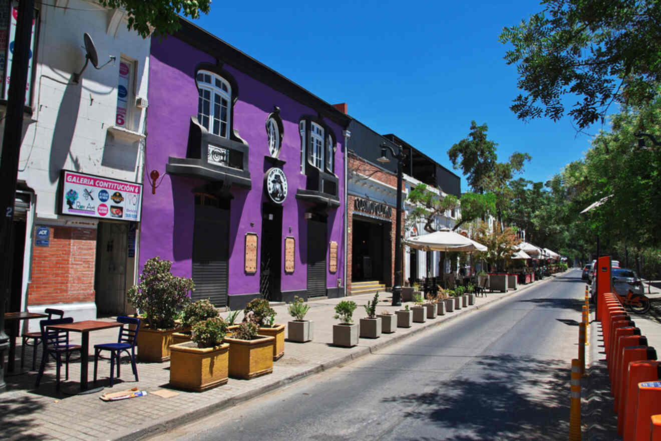 Colorful street view in the Bellavista neighborhood of Santiago, Chile, with vibrant purple buildings and sidewalk cafes
