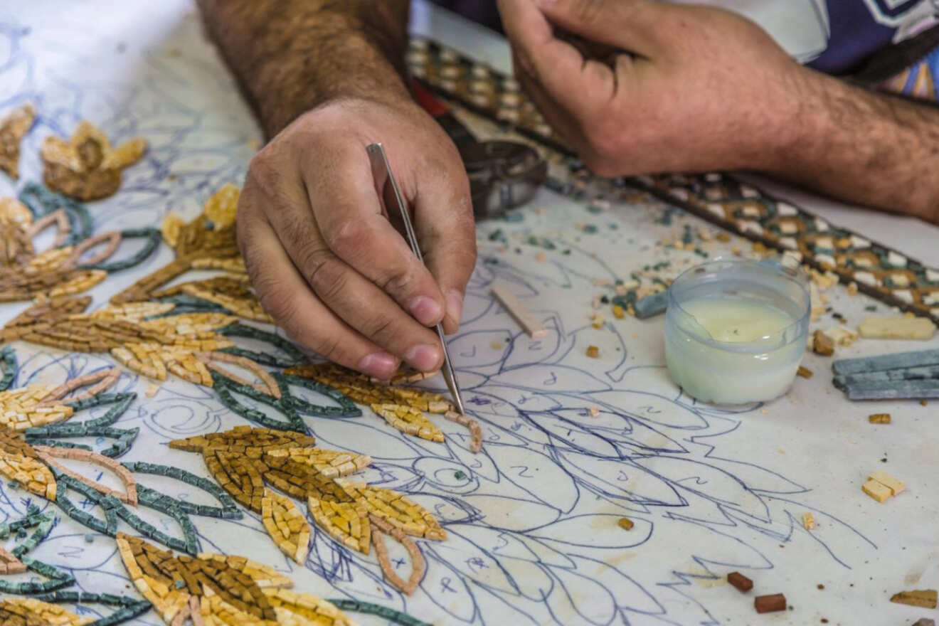 A detailed shot of a craftsman's hands working on a traditional mosaic piece in Amman, Jorda