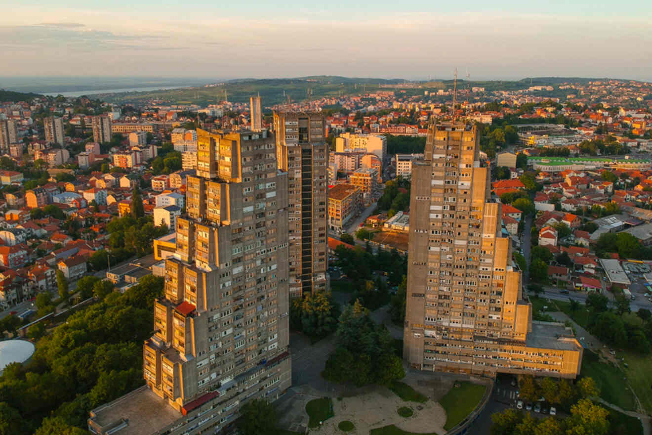 A view of the East Gate Towers, a striking example of brutalist architecture in Belgrade, standing tall against the backdrop of a sunset sky