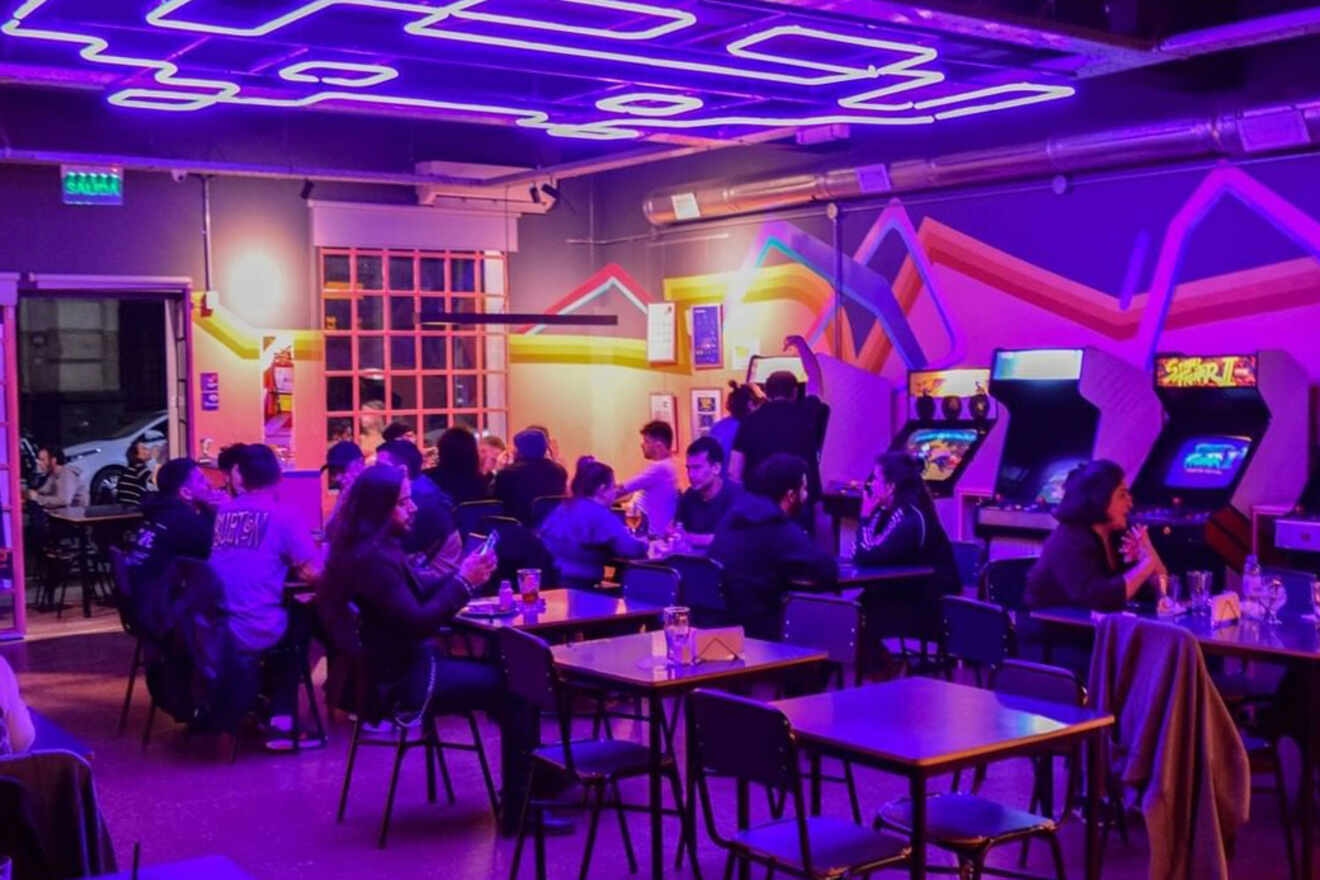 Vibrant nightlife scene at El Destello, Buenos Aires, with patrons enjoying drinks and retro arcade games under neon blue lights