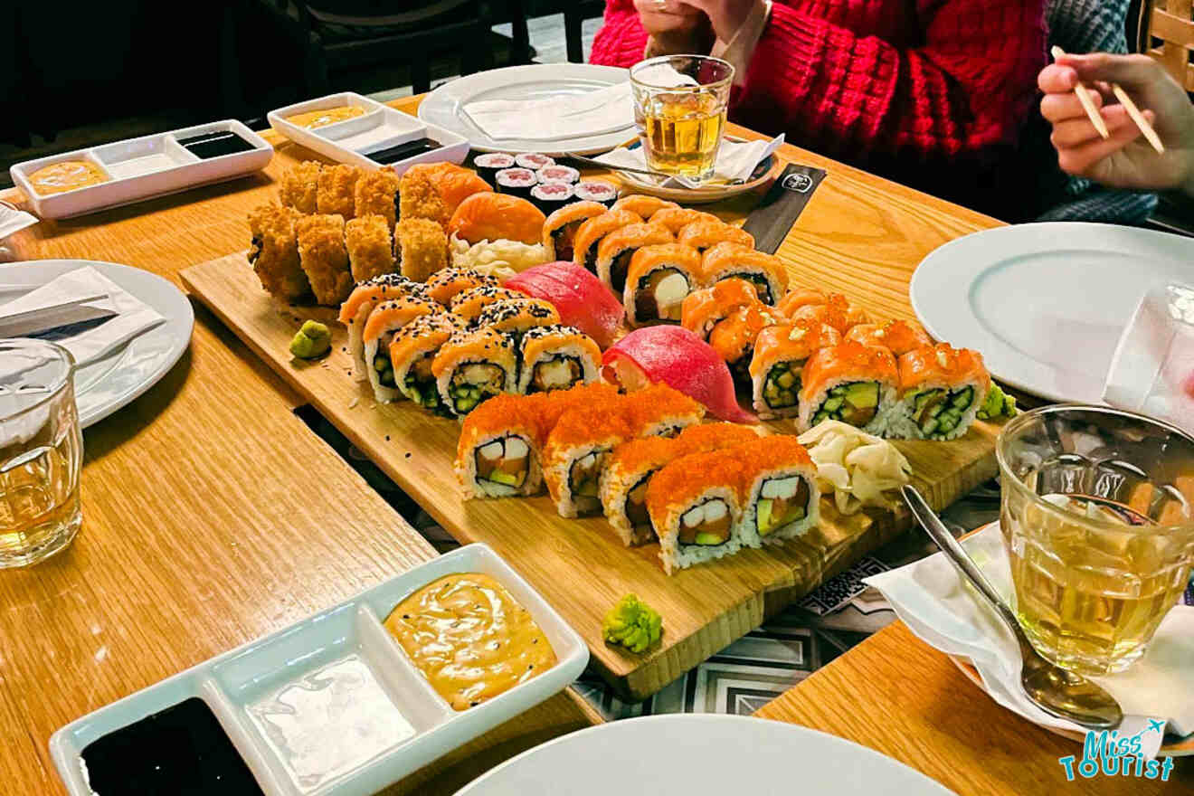 A delightful sushi platter with an assortment of rolls and nigiri, accompanied by soy sauce, wasabi, and ginger, on a wooden board at a Tel Aviv restaurant
