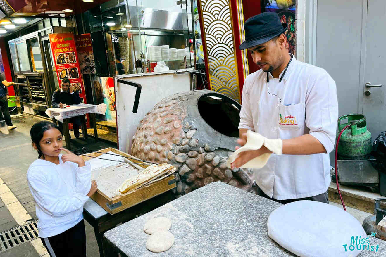 A cooking class in Amman, Jordan, showing a chef stretching dough while a young girl looks on
