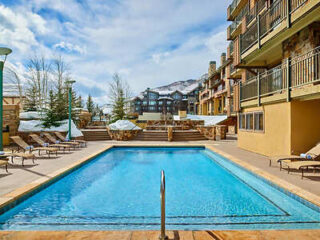 Outdoor swimming pool at a ski resort, with sun loungers