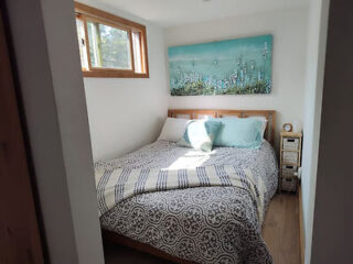 Cozy bedroom in Darling Tiny House with patterned bedding and a teal accent wall art