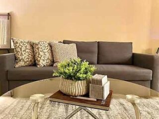 An elegant corner in a hotel lounge with a sleek gray sofa, a contemporary coffee table, and a fresh green centerpiece bringing life to the space.