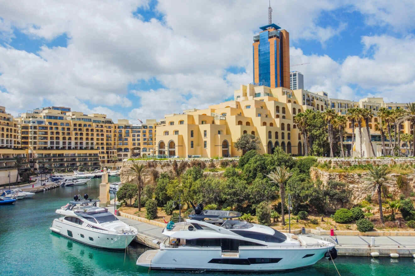 Luxury yachts moored in the calm waters of Portomaso Marina, with the modern Portomaso Business Tower overlooking the traditional terraced apartments and palm trees in St. Julian's, Malta.